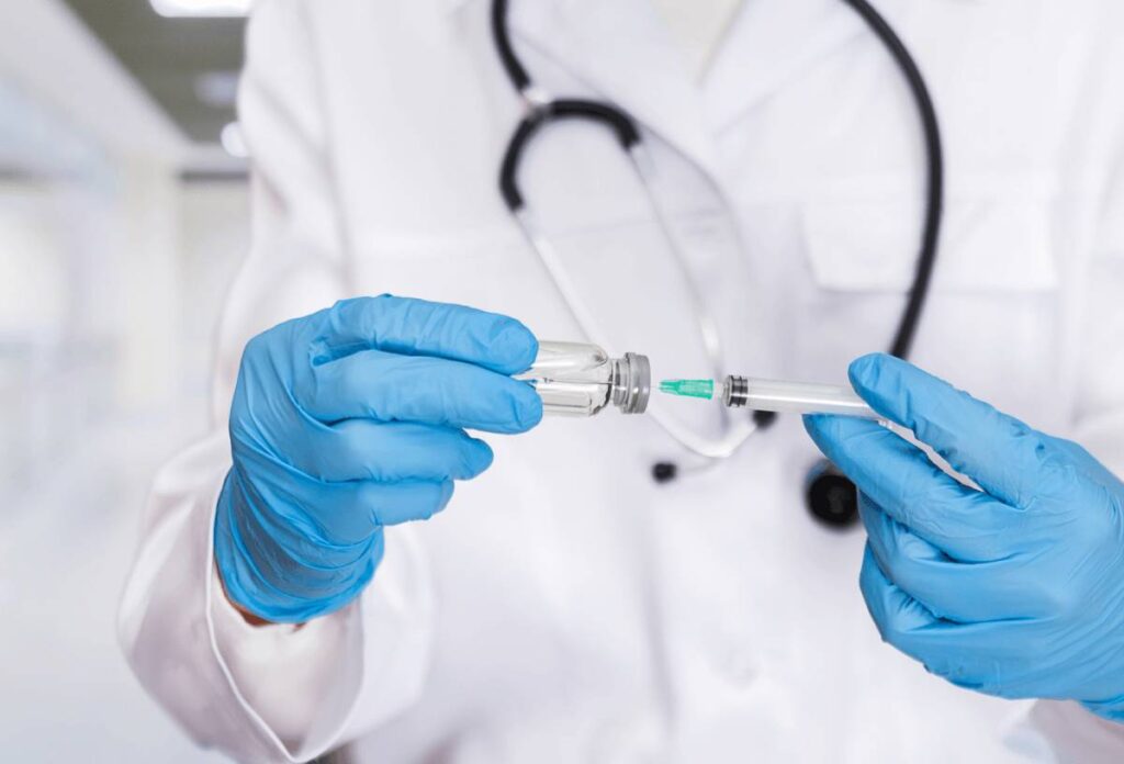 A doctor in blue surgical gloves preparing an allergen immunotherapy injection in a clinical setting